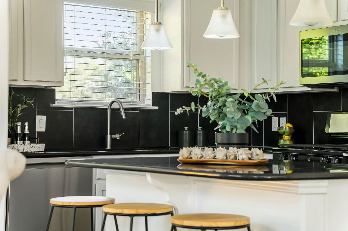 800 Totis Road Austin, TX 78748 - Photo 9 of 29 Kitchen featuring a kitchen bar, stainless steel appliances, dark stone countertops, white cabinets, and tasteful backsplash