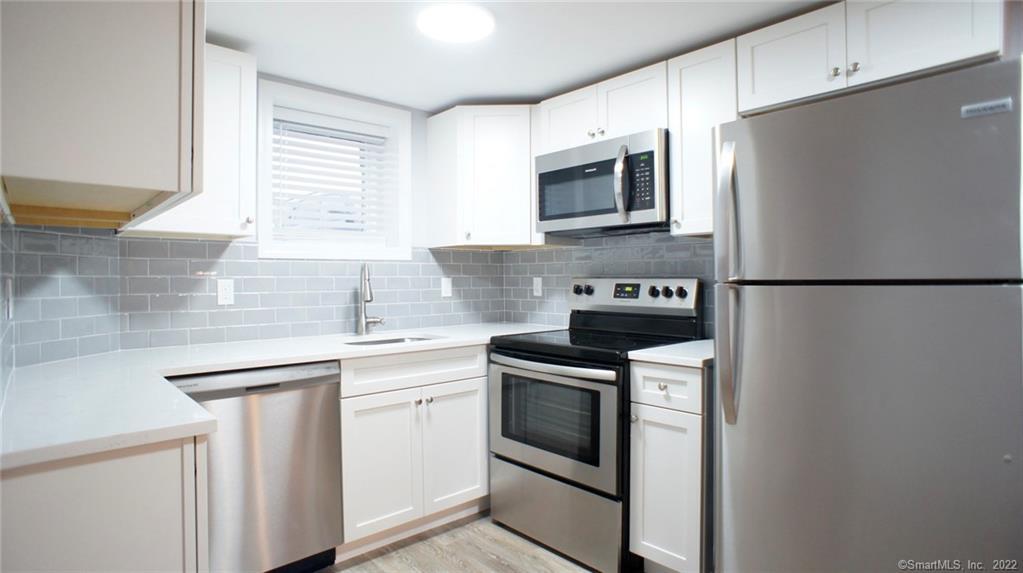 a kitchen with stainless steel appliances granite countertop white cabinets a microwave a sink and a refrigerator
