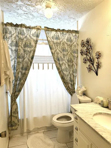 a bathroom with a granite countertop sink and a toilet
