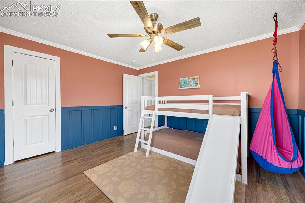 17520 Fremont Fort Road Peyton, CO 80831 - Photo 18 of 42 This room features hardwood flooring, white crown molding, custom wainscoting and a ceiling fan with integrated lighting