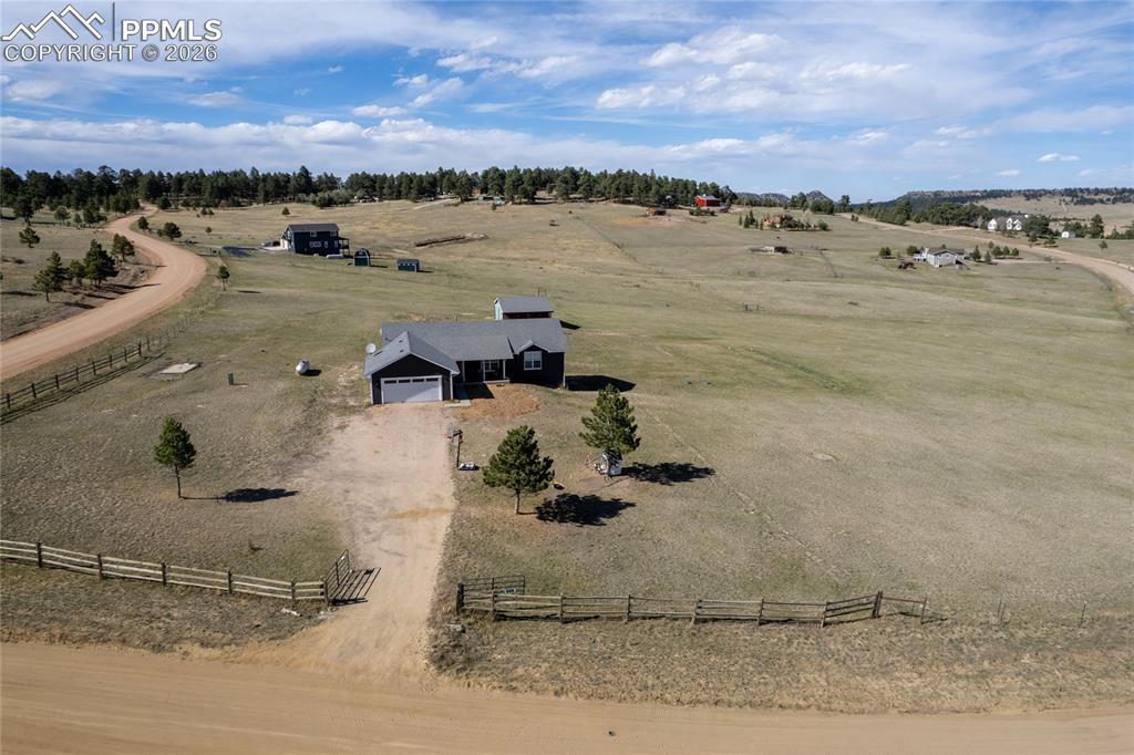 17520 Fremont Fort Road Peyton, CO 80831 - Photo 2 of 42 The property features a dark exterior with a light-colored roof, a front-facing garage, and a gravel driveway
