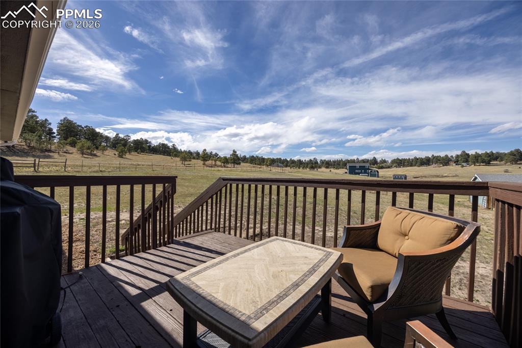 17520 Fremont Fort Road Peyton, CO 80831 - Photo 33 of 42 The property features an outdoor deck with wood railing, offering expansive views of open fields and distant trees
