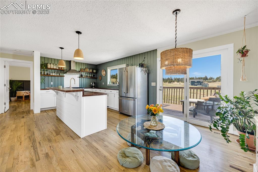 17520 Fremont Fort Road Peyton, CO 80831 - Photo 5 of 42 The kitchen and dining area features hardwood floors, white cabinetry, and stainless steel appliances