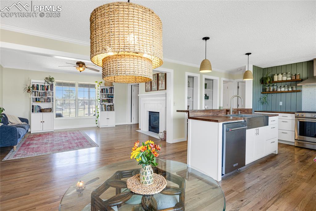 17520 Fremont Fort Road Peyton, CO 80831 - Photo 6 of 42 Spacious open-concept living area featuring hardwood flooring, a fireplace with a white mantel, and a kitchen island with a farmhouse sink