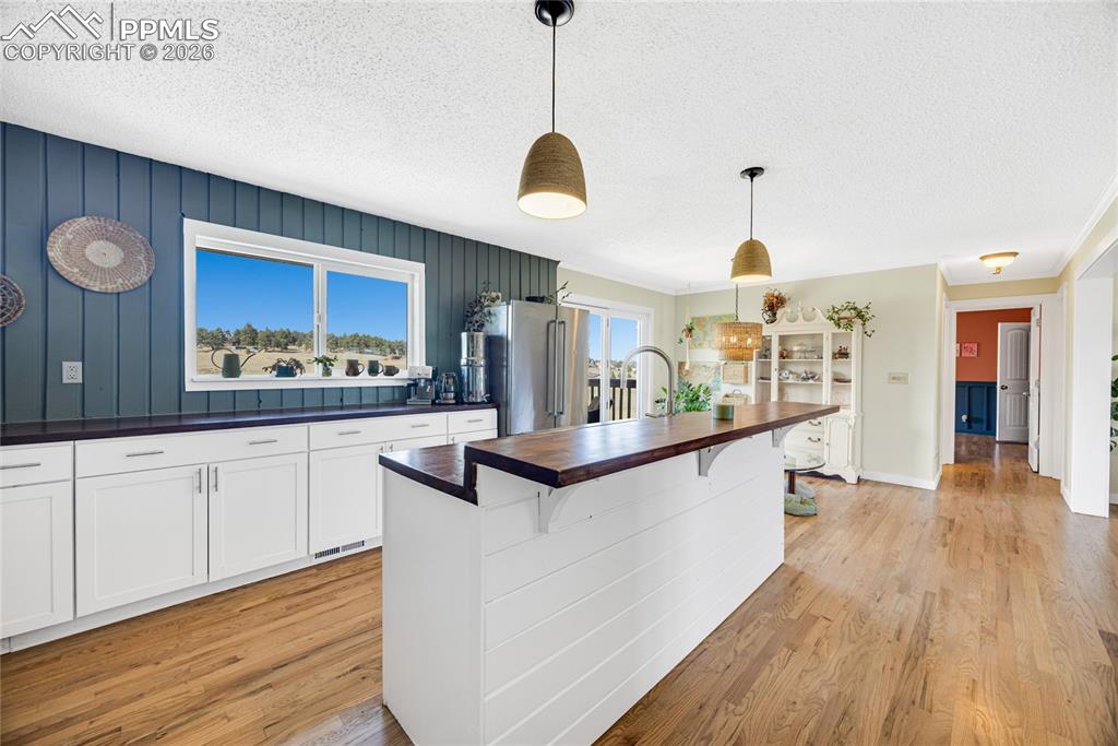 17520 Fremont Fort Road Peyton, CO 80831 - Photo 9 of 42 The property features hardwood flooring throughout, white cabinetry with dark countertops, and an island with a wooden countertop