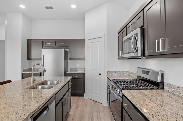 a kitchen with stainless steel appliances granite countertop a sink stove and refrigerator