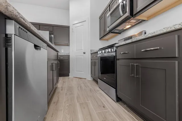 a view of a garage with stainless steel appliances wooden floor and staircase
