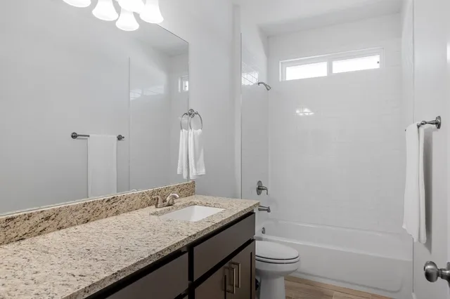 a bathroom with a granite countertop sink a toilet and shower