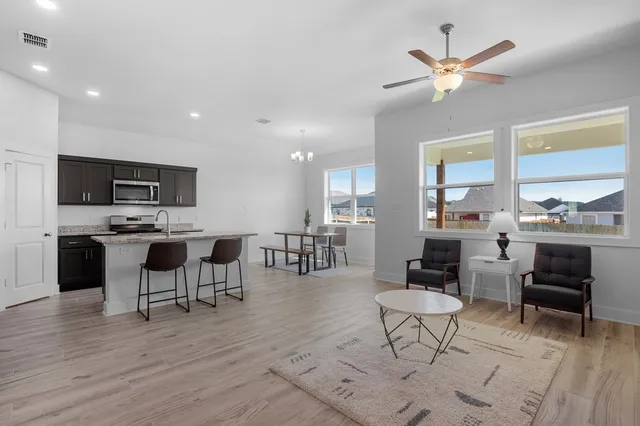 a living room with furniture kitchen view and a wooden floor