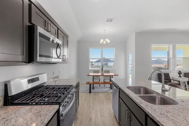 a kitchen with granite countertop a sink a stove and cabinets