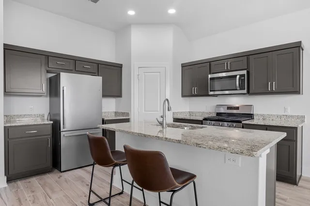 a kitchen with stainless steel appliances granite countertop a refrigerator stove microwave and sink