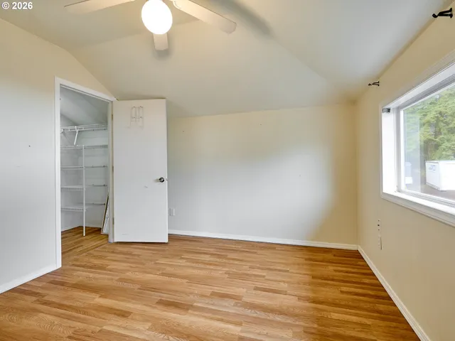 an empty room with wooden floor fan and windows