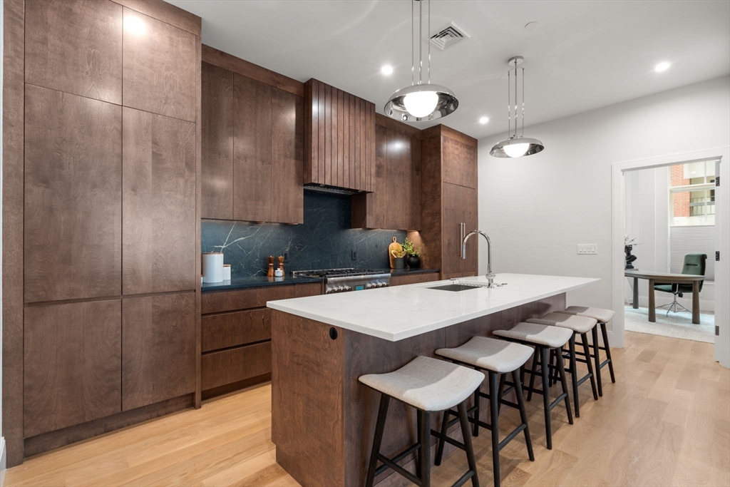 67 Church Street, Unit 1 Boston, MA 02116 - Photo 7 of 15 a kitchen with stainless steel appliances kitchen island granite countertop a sink a stove a refrigerator and island with wooden floor