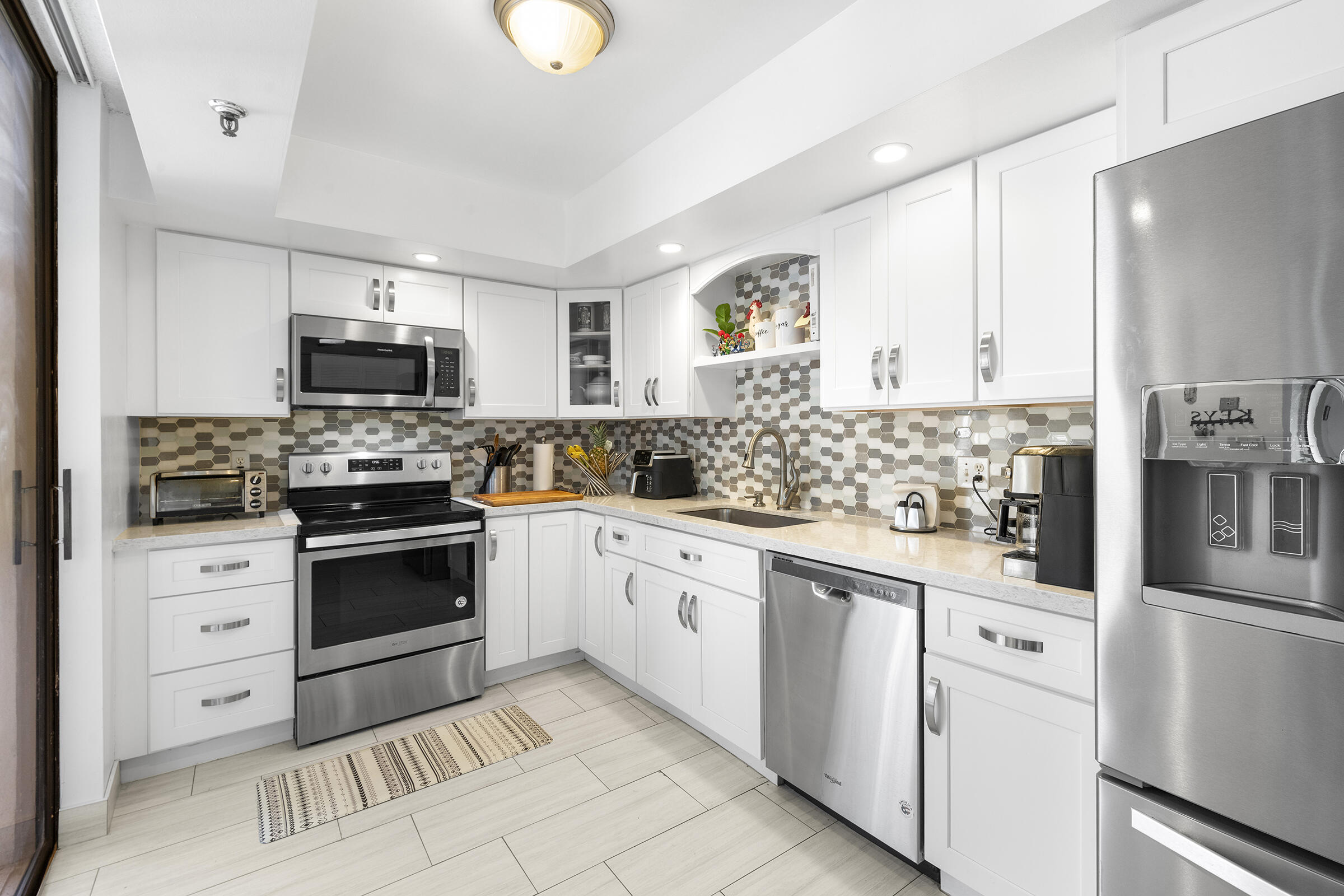 6845 Willow Wood Drive, Unit 3012 Boca Raton, FL 33434 - Photo 15 of 28 a kitchen with white cabinets and appliances