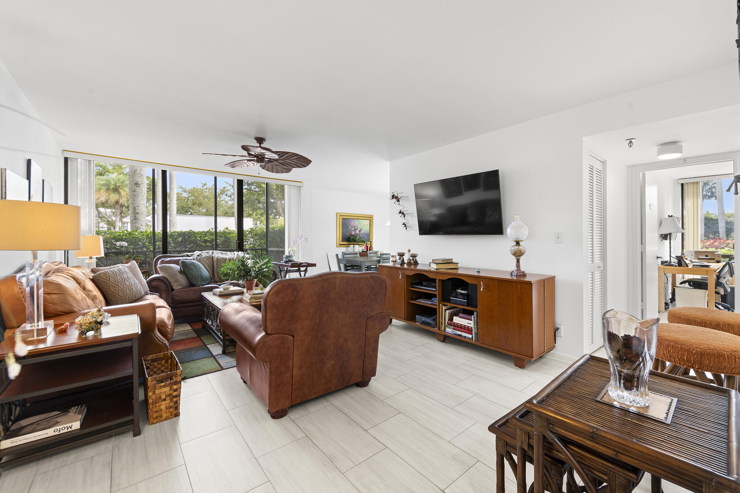 6845 Willow Wood Drive, Unit 3012 Boca Raton, FL 33434 - Photo 2 of 28 a living room with furniture a flat screen tv and a floor to ceiling window