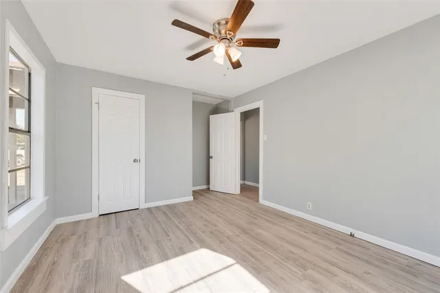 an empty room with wooden floor and a ceiling fan