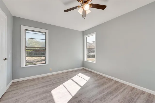 a view of empty room with wooden floor and fan