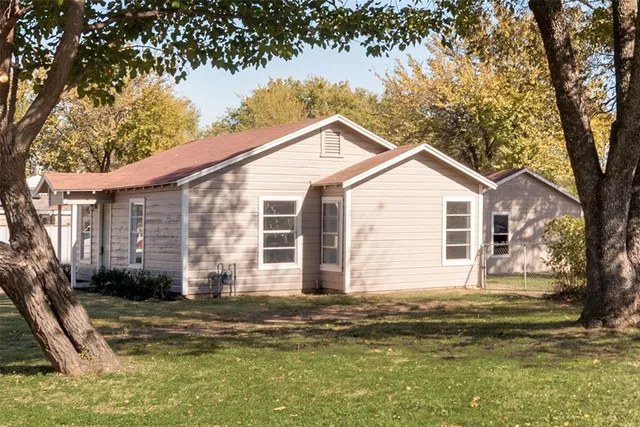 a view of a house with a large tree and a yard