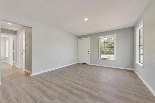 a view of an empty room with wooden floor and window