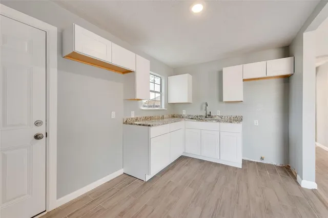 a kitchen with granite countertop white cabinets and wooden floor