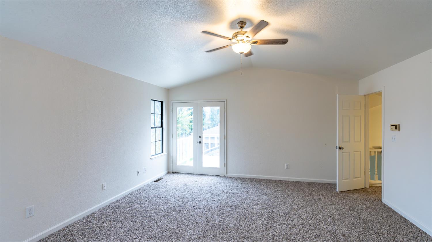 12501 Riverside Road Waterford, CA 95386 - Photo 18 of 24 an empty room with chandelier fan and windows
