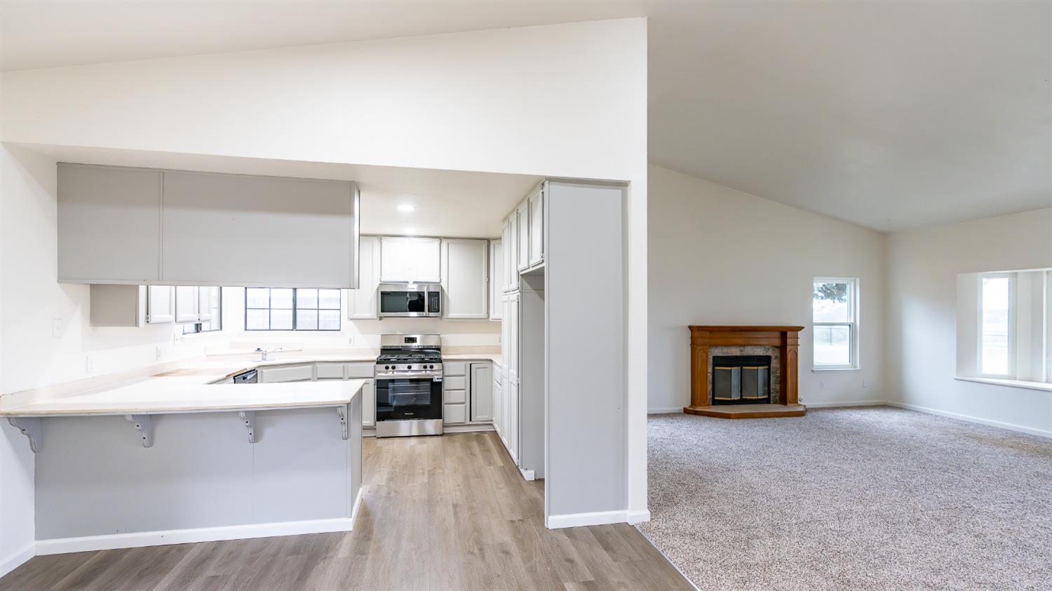 12501 Riverside Road Waterford, CA 95386 - Photo 6 of 24 a kitchen with stainless steel appliances granite countertop a refrigerator a stove a sink and a fireplace with wooden floor
