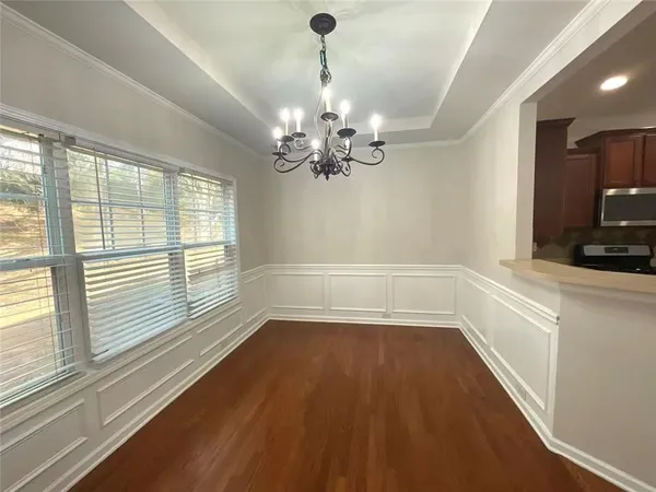 an empty room with wooden floor chandelier fan and windows