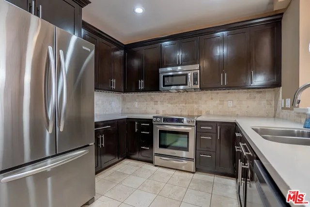 a kitchen with stainless steel appliances granite countertop a refrigerator and a sink