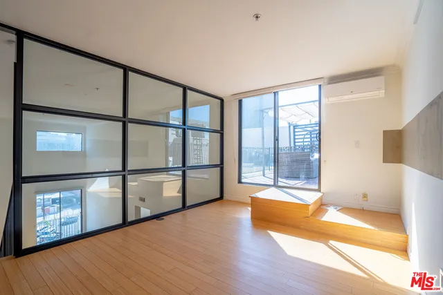 a view of an empty room with window and wooden floor