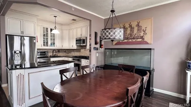 a kitchen with stainless steel appliances granite countertop a stove a refrigerator a dining table and chairs with wooden floor