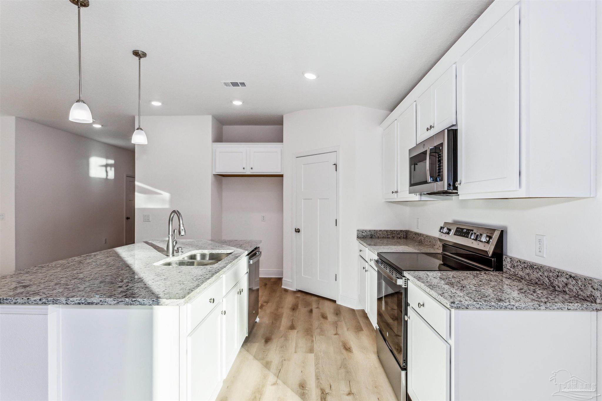 5009 Rainwater Road Milton, FL 32583 - Photo 17 of 29 a kitchen with a sink a stove a microwave and refrigerator
