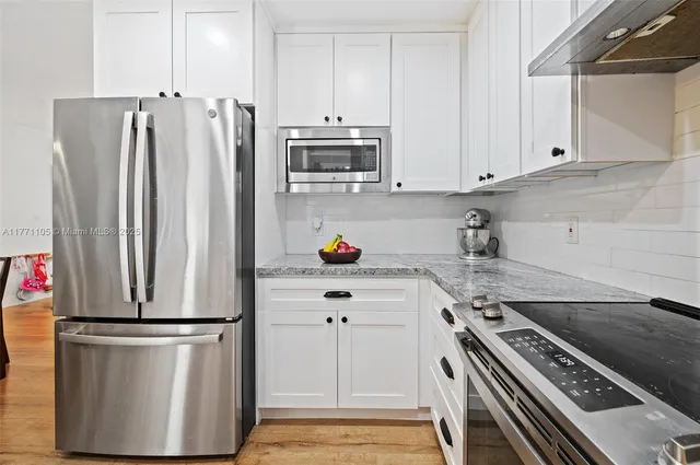a kitchen with stainless steel appliances a refrigerator a stove and white cabinets