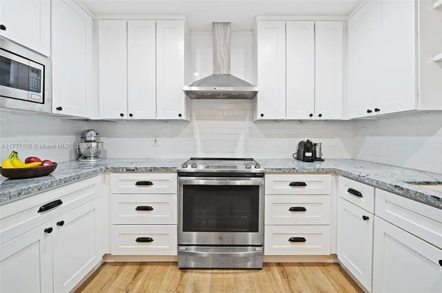 a kitchen with granite countertop white cabinets and white appliances