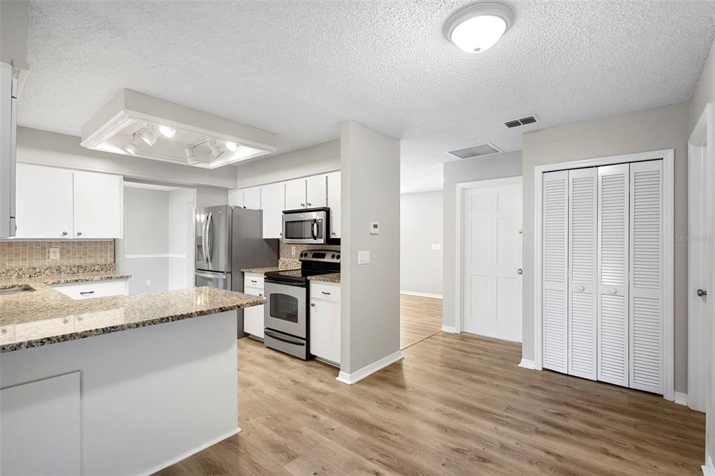 1031 Abeline Drive Deltona, FL 32725 - Photo 20 of 37 a kitchen with kitchen island granite countertop a refrigerator oven a sink dishwasher and white cabinets with wooden floor