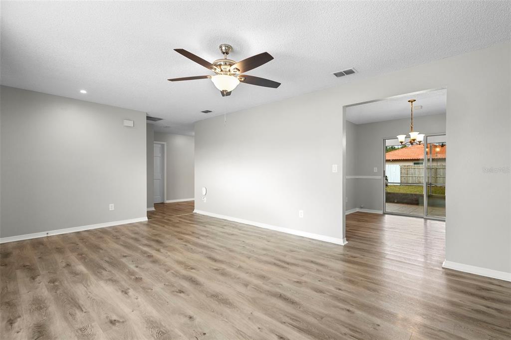 1031 Abeline Drive Deltona, FL 32725 - Photo 9 of 37 a view of an empty room with wooden floor and a ceiling fan
