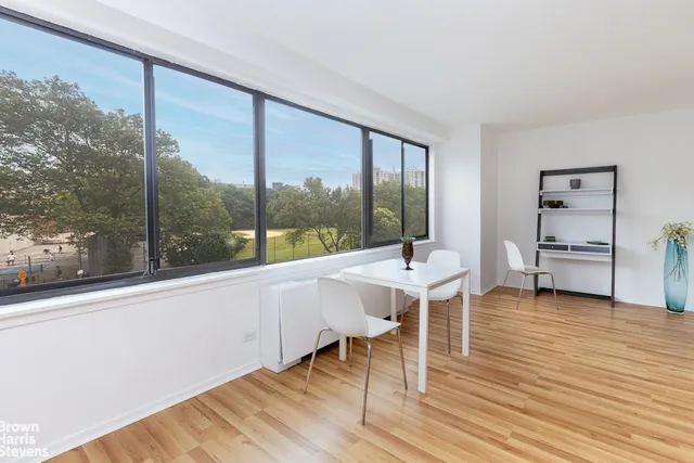a dining room with wooden floor and a floor to ceiling window