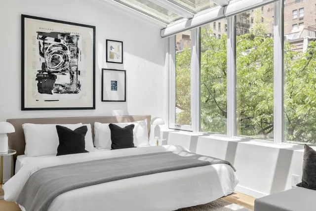 a bedroom with a large bed and a large window with the outer view