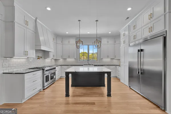 a kitchen with stainless steel appliances granite countertop a kitchen island hardwood floor sink and stove