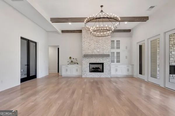 a view of a livingroom with a fireplace a chandelier and wooden floor