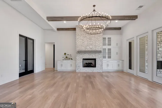 a view of a livingroom with a fireplace a chandelier and wooden floor