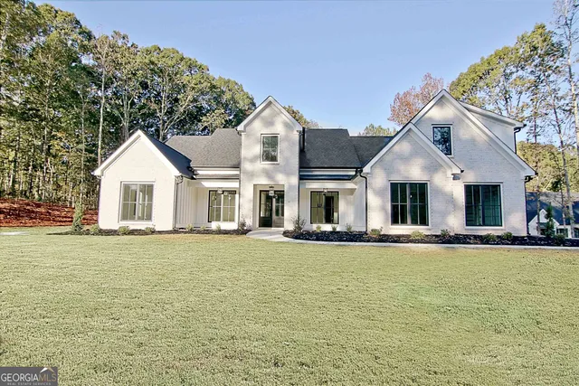 a front view of a house with a garden and lake view