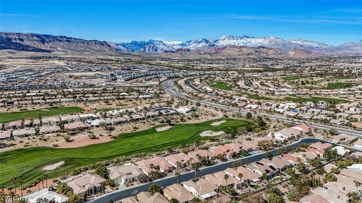 5015 Rivedro Street Las Vegas, NV 89135 - Photo 89 of 91 An aerial perspective reveals a vibrant community nestled among verdant golf courses with a dramatic mountain backdrop.