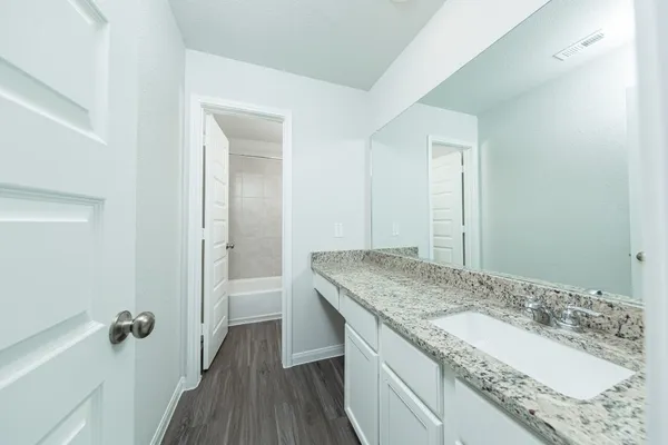 a bathroom with a granite countertop sink a toilet and shower