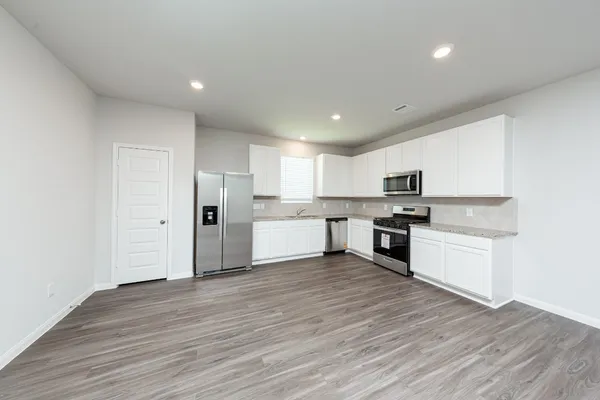 a view of kitchen with granite countertop cabinets and refrigerator