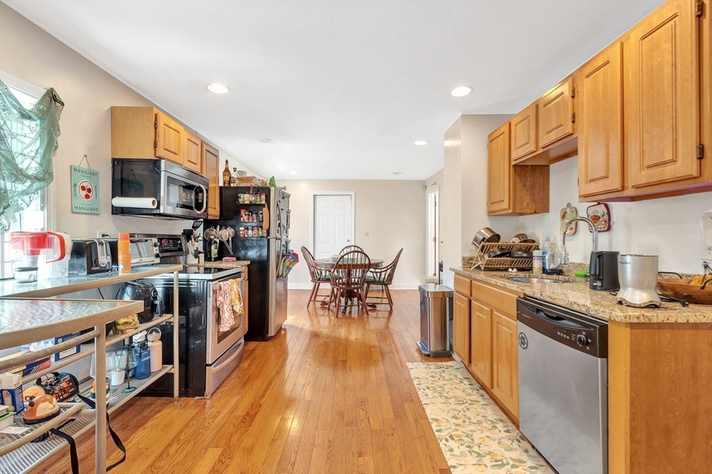 22 Fisher Avenue, Unit 1 Boston, MA 02120 - Photo 4 of 8 a kitchen with stainless steel appliances granite countertop a stove top oven a sink dishwasher a dining table and chairs with wooden floor