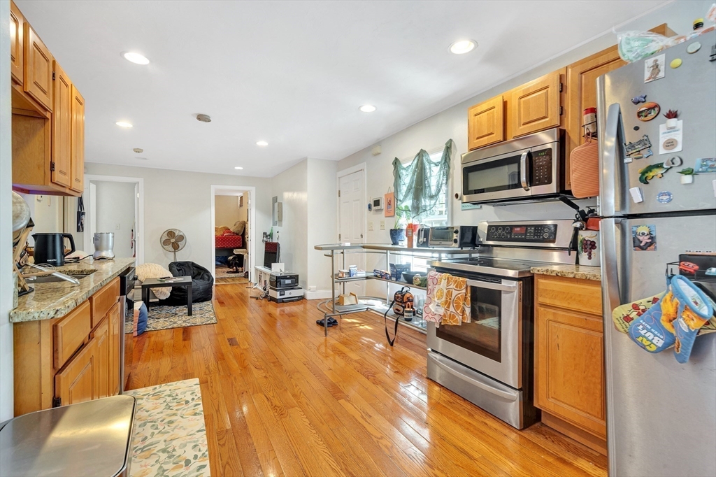 22 Fisher Avenue, Unit 1 Boston, MA 02120 - Photo 5 of 8 a living room with stainless steel appliances furniture a flat screen tv and a kitchen view