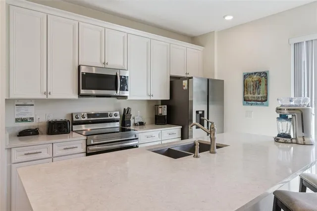 a kitchen with a sink a counter space and a view of living room