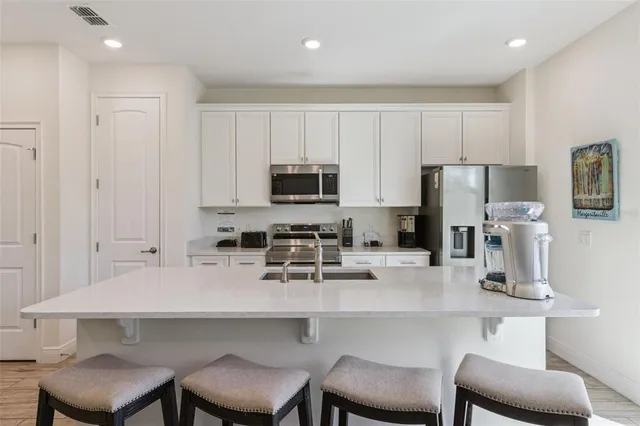 a kitchen with stainless steel appliances kitchen island granite countertop a refrigerator a stove a sink dishwasher a dining table and chairs with wooden floor