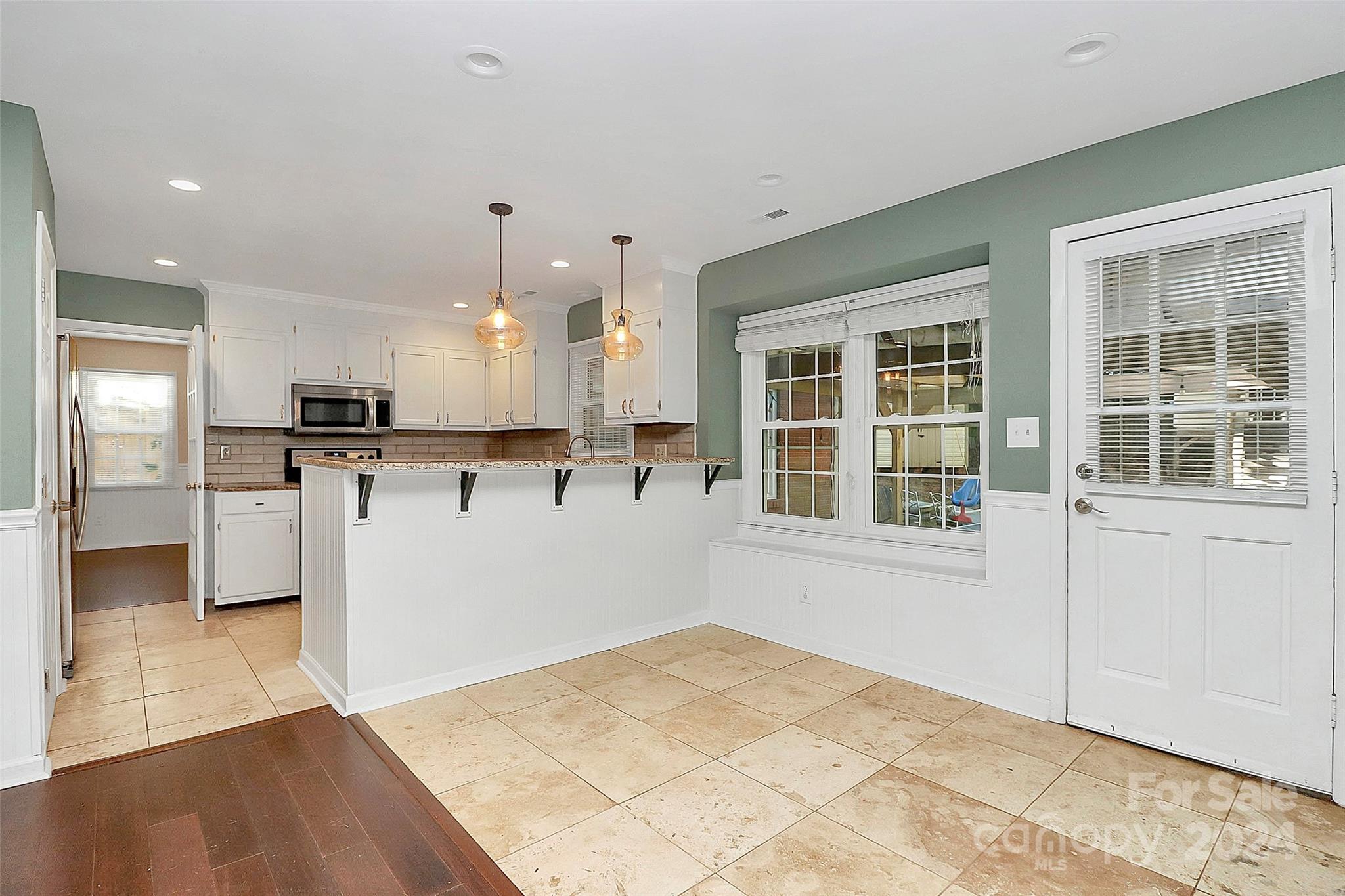 623 Trail Ridge Road Matthews, NC 28105 - Photo 10 of 38 a view of a kitchen with kitchen island a sink wooden floor and a large window