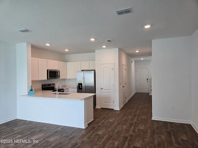 a kitchen with stainless steel appliances a refrigerator sink and white cabinets